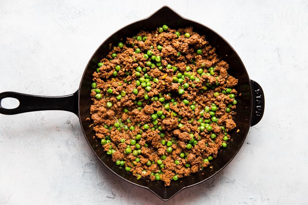 ground beef, peas and ginger cooked in a cast iron skillet