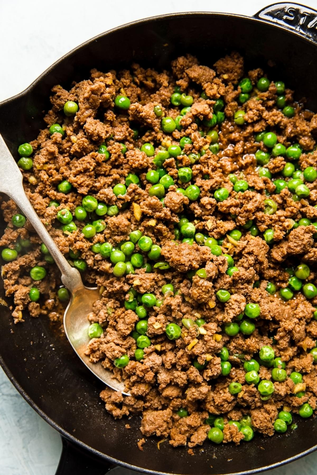 ground beef, peas and ginger in a cast iron skillet soboro donburi with a spoon