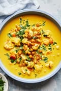 a bowl of homemade golden soup made with carrots, chickpeas, cauliflower, turmeric, ginger and coconut milk