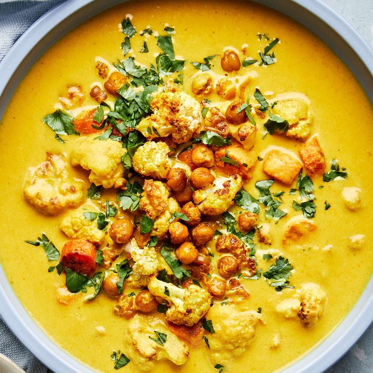 a bowl of homemade golden soup made with carrots, chickpeas, cauliflower, turmeric, ginger and coconut milk