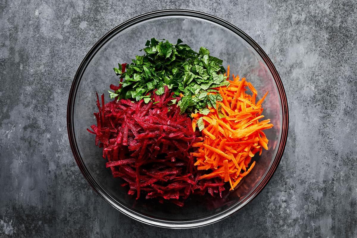 grated beet, grated carrot, parsley and mint in a large glass bowl