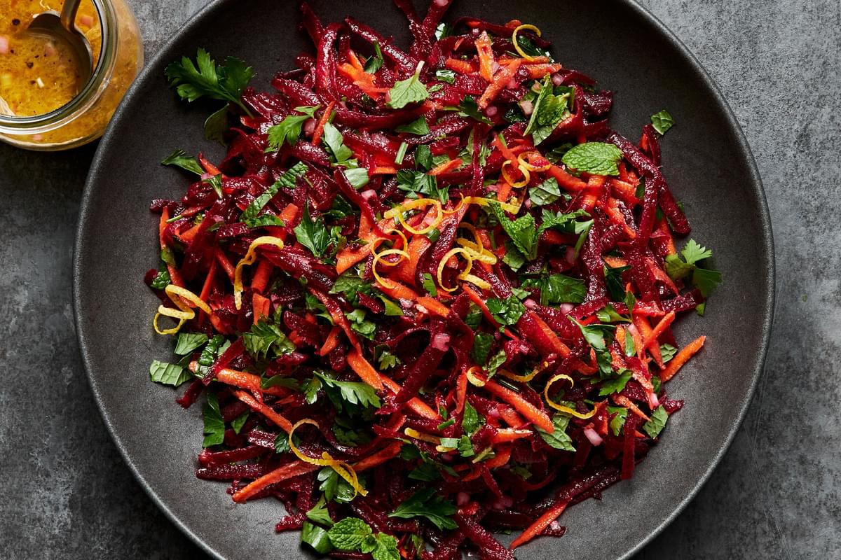 grated beet salad made with grated carrots, parsley, mint and homemade honey mustard dressing in a serving bowl