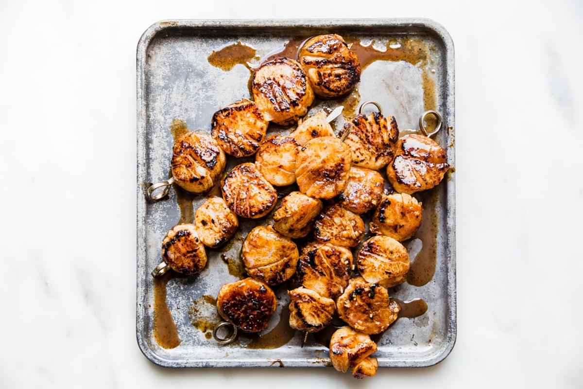 Grilled sea scallops hot off the grill resting on a baking sheet.