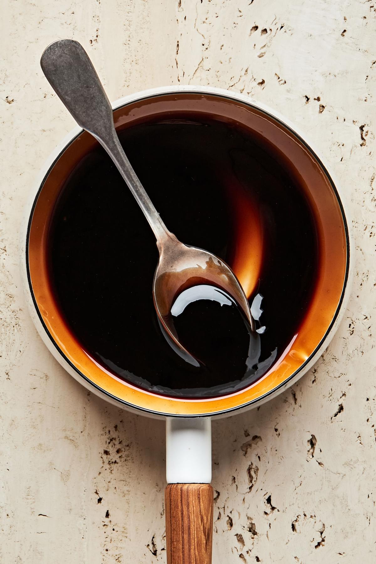 Balsamic reduction in a pot with a spoon. Made with balsamic vinegar, sugar, salt and cornstarch