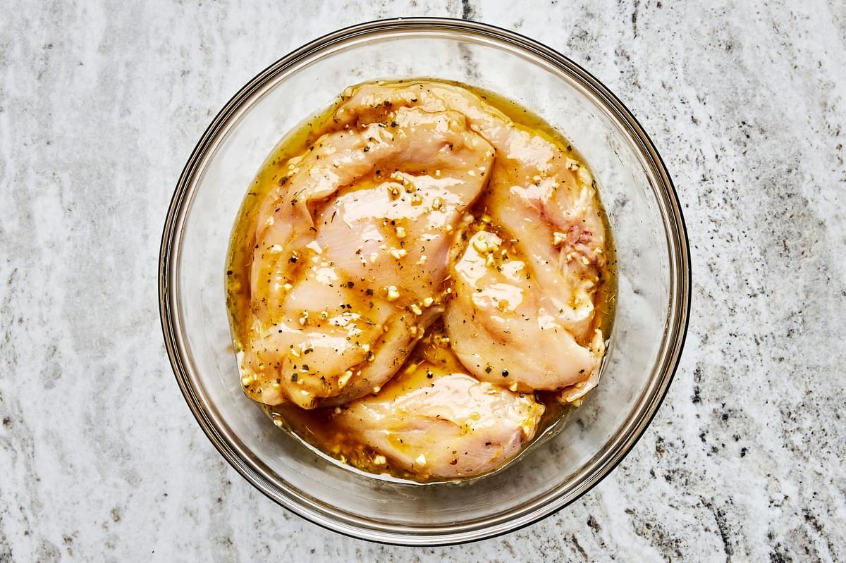 chicken being marinated in olive oil, garlic, thyme, basil, salt, pepper, lemon zest, Dijon, Worcestershire & brown sugar