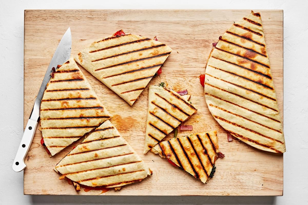 grilled chicken quesadillas being sliced on a wooden cutting board