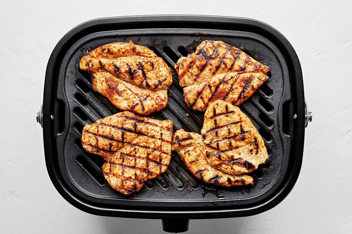 4 butterflied chicken breasts seasoned with taco seasoning being cooked on the grill