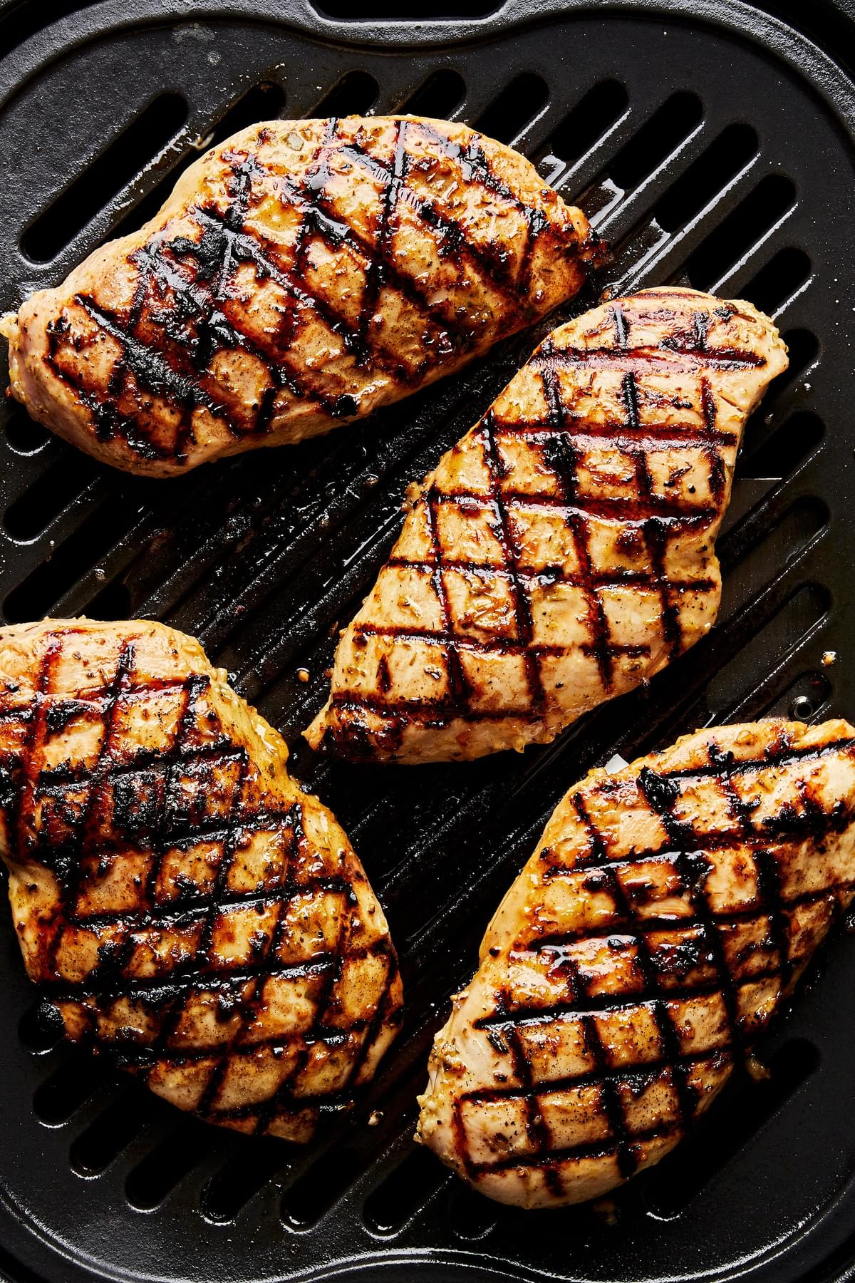 4 chicken breasts cooking on a grill