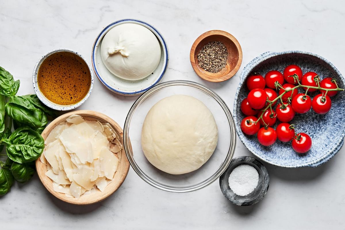 pizza dough ball, burrata, olive oil, salt, pepper, shaved parmesan and cherry tomatoes in prep bowl