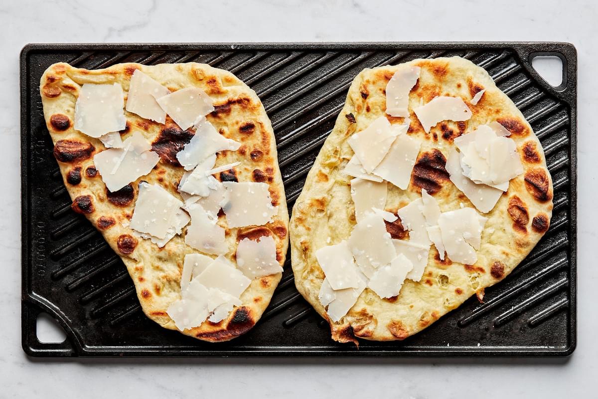grilled flatbread cooking on a grill topped with parmesan cheese