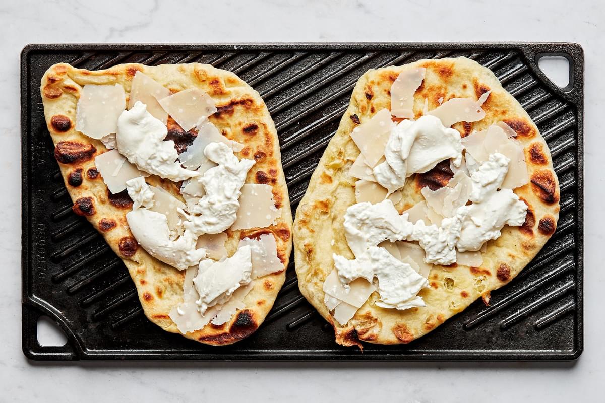 grilled flatbread cooking on a grill topped with parmesan and burrata cheese