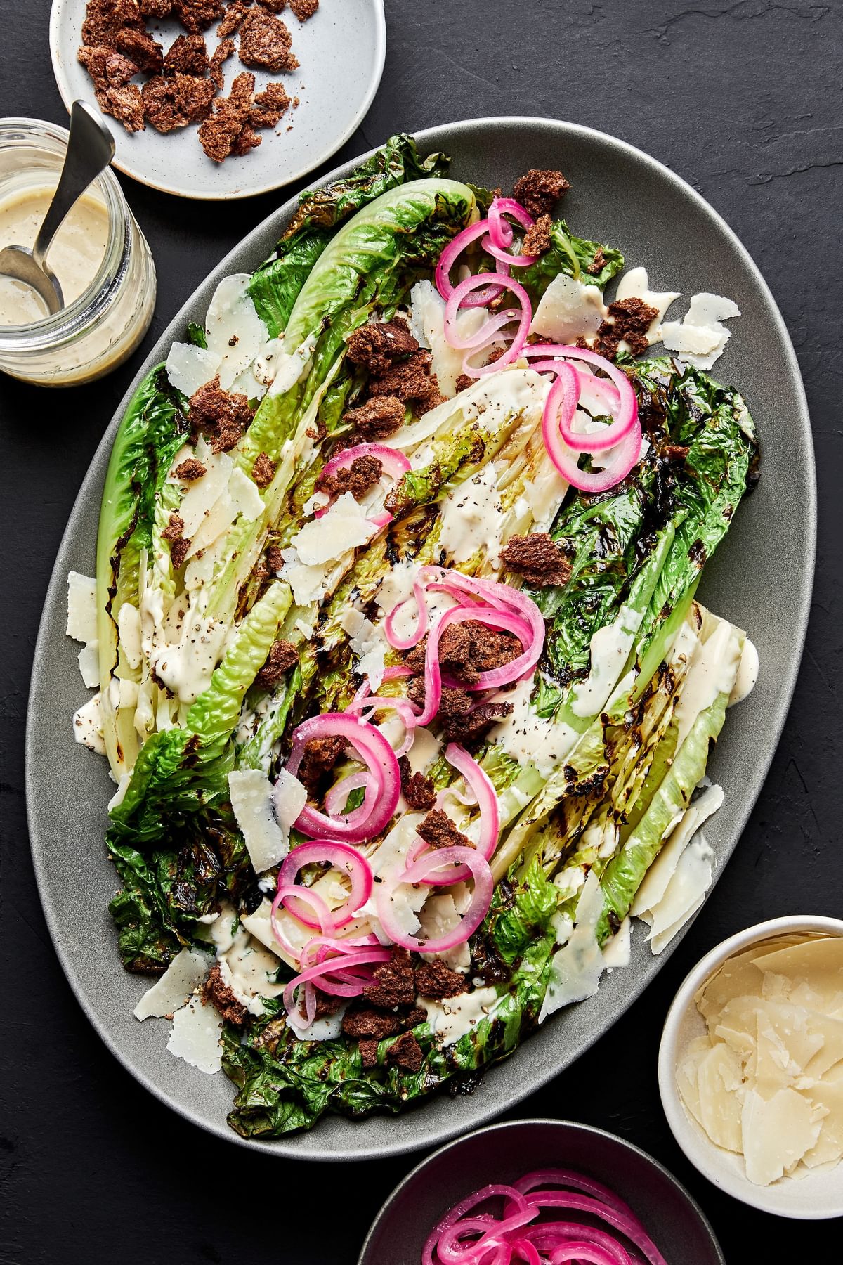 grilled romaine caesar salad with homemade dressing and topped with pickled onions and homemade breadcrumbs