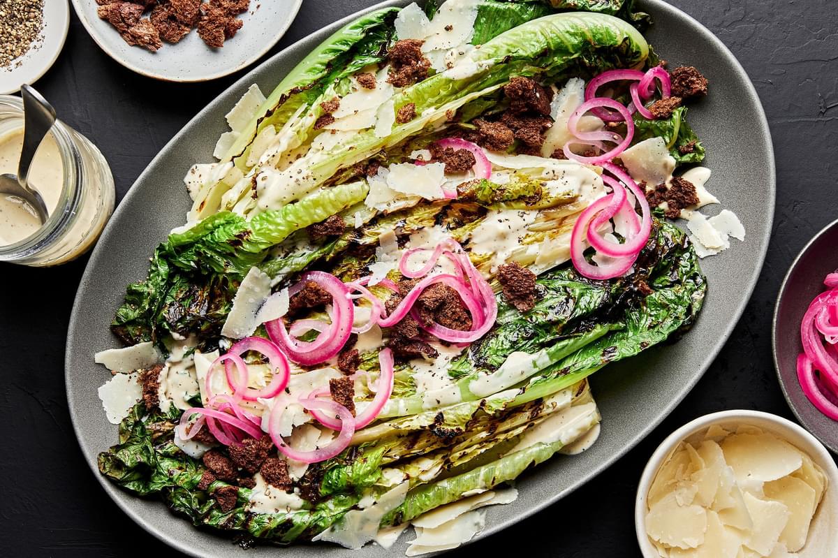 grilled Romaine Caesar salad with homemade dressing and topped with pickled onions and homemade breadcrumbs