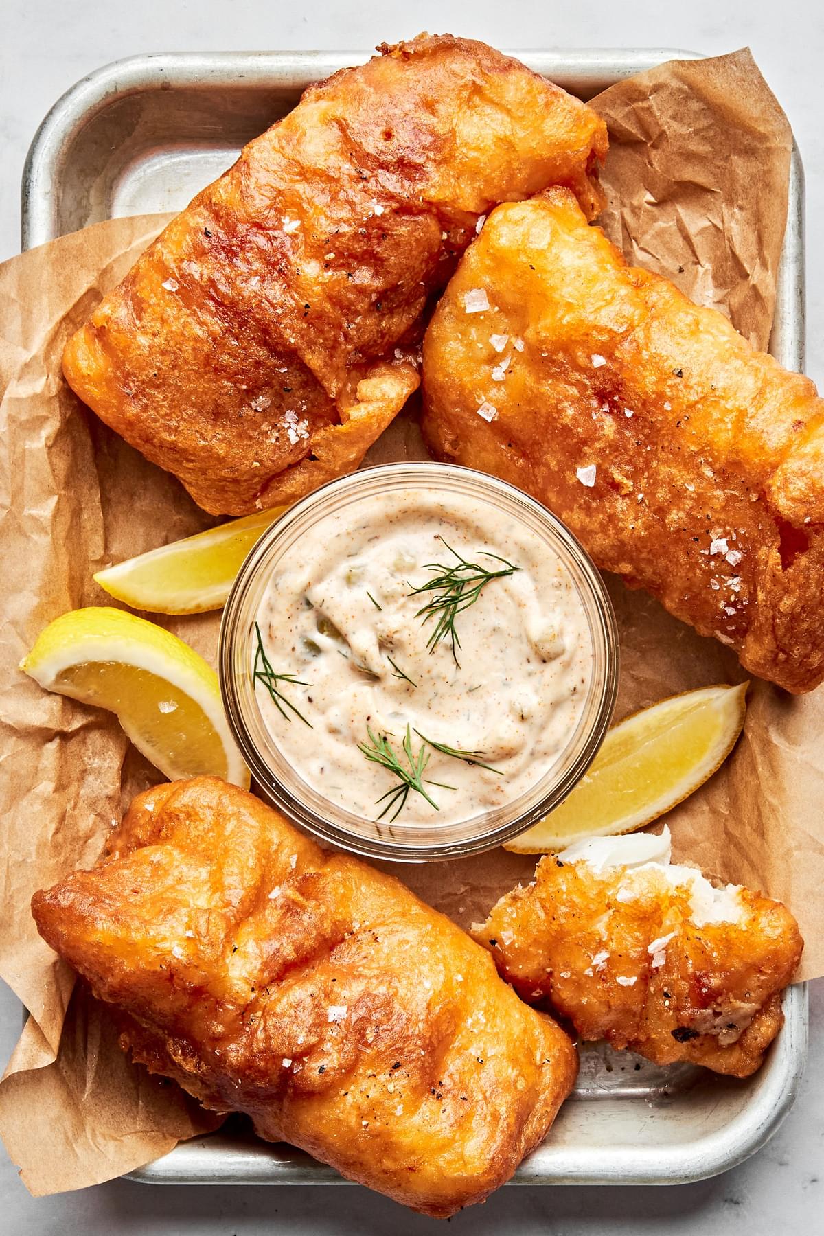 a bowl of homemade tartar sauce surrounded by beer battered fish and fries