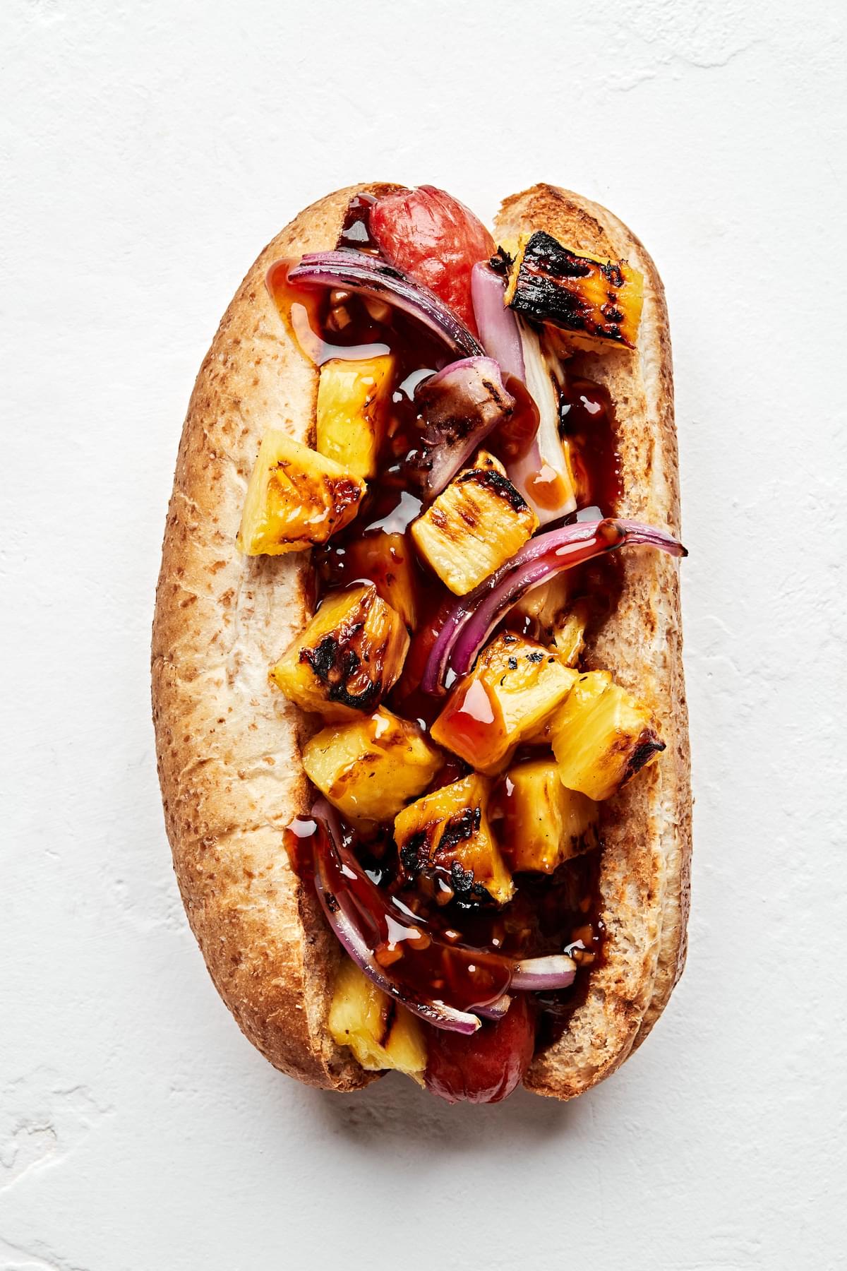 hawaiian hot dog topped with grilled pineapple, red onions and teriyaki sauce