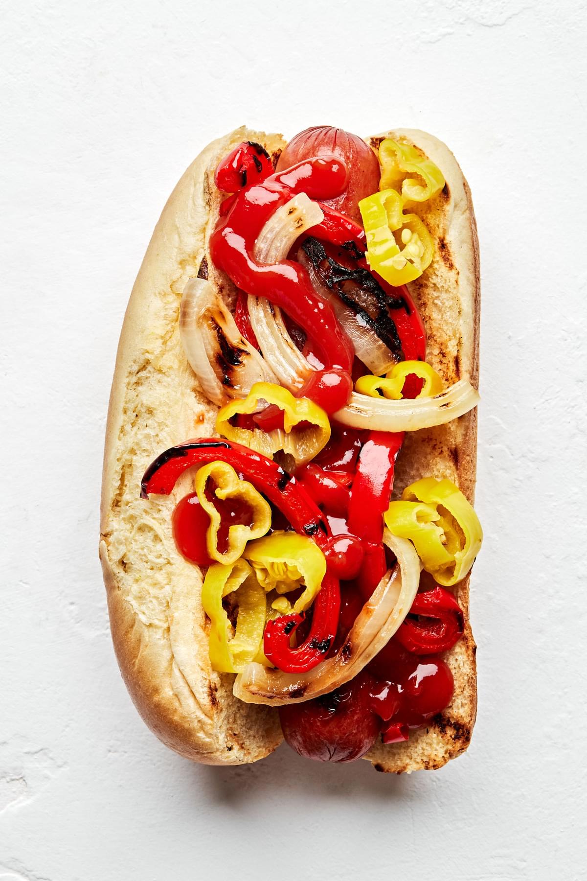 Italian-American hot dog topped with Grilled onions and bell peppers, ketchup, and pepperoncinis