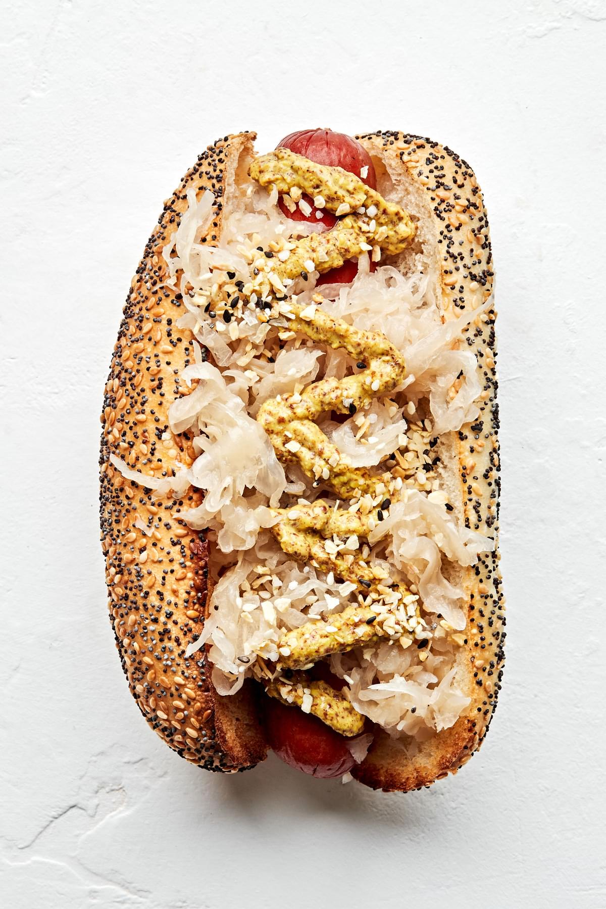 A Deli style hot dog topped with sauerkraut, curry mustard and everything bagel seasoning.