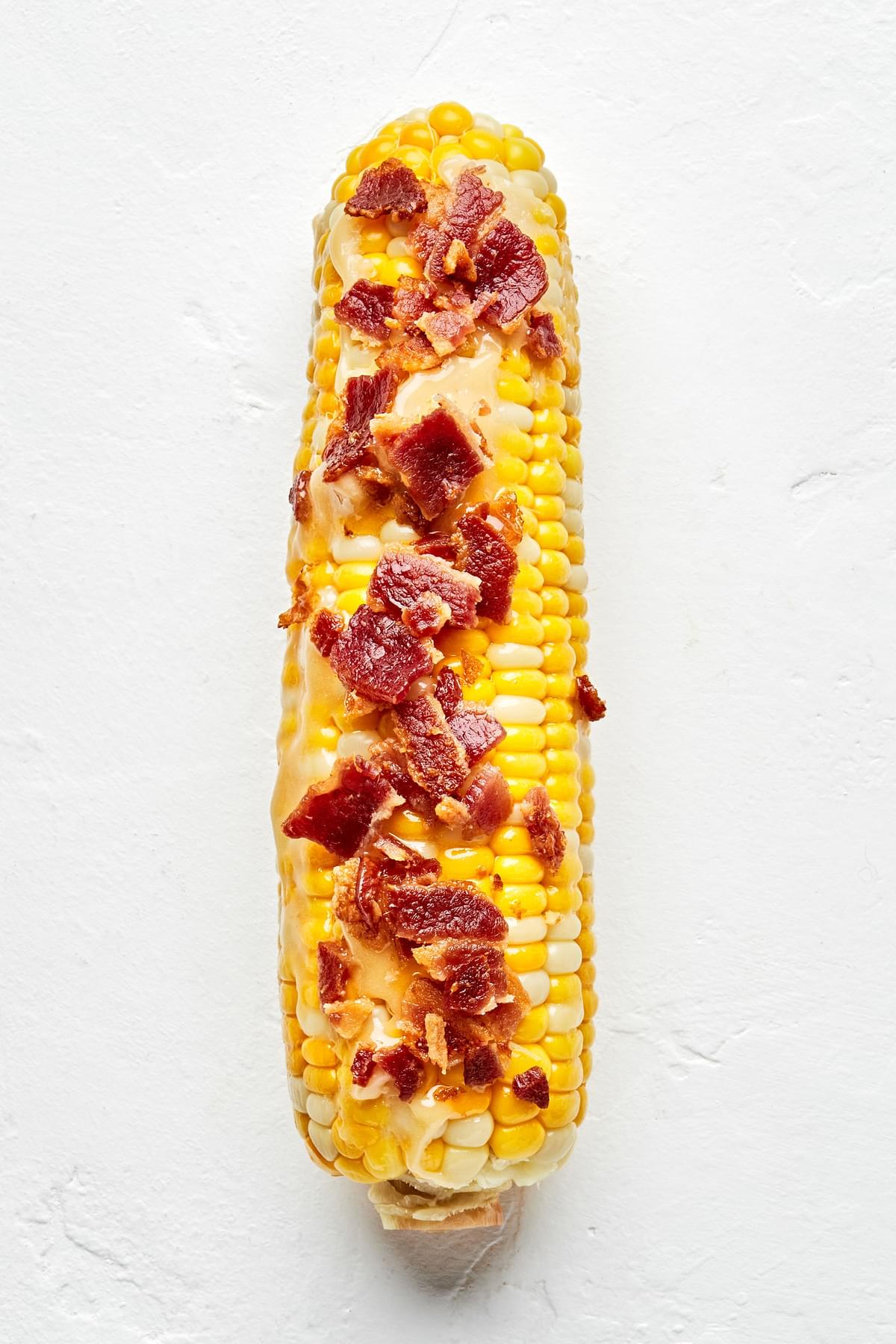 a grilled corn on the cob with maple bourbon butter and crumbled bacon