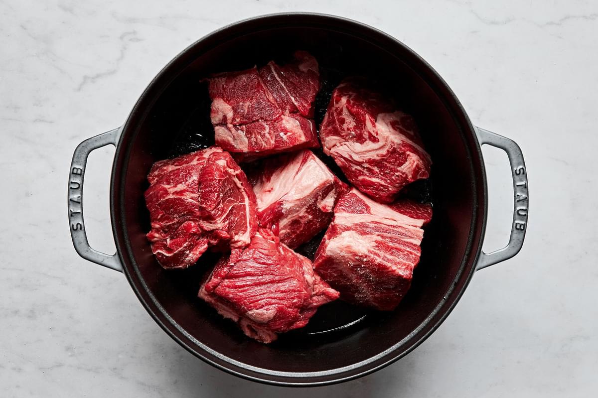 salted chunks of chuck roast being cooked in a pot