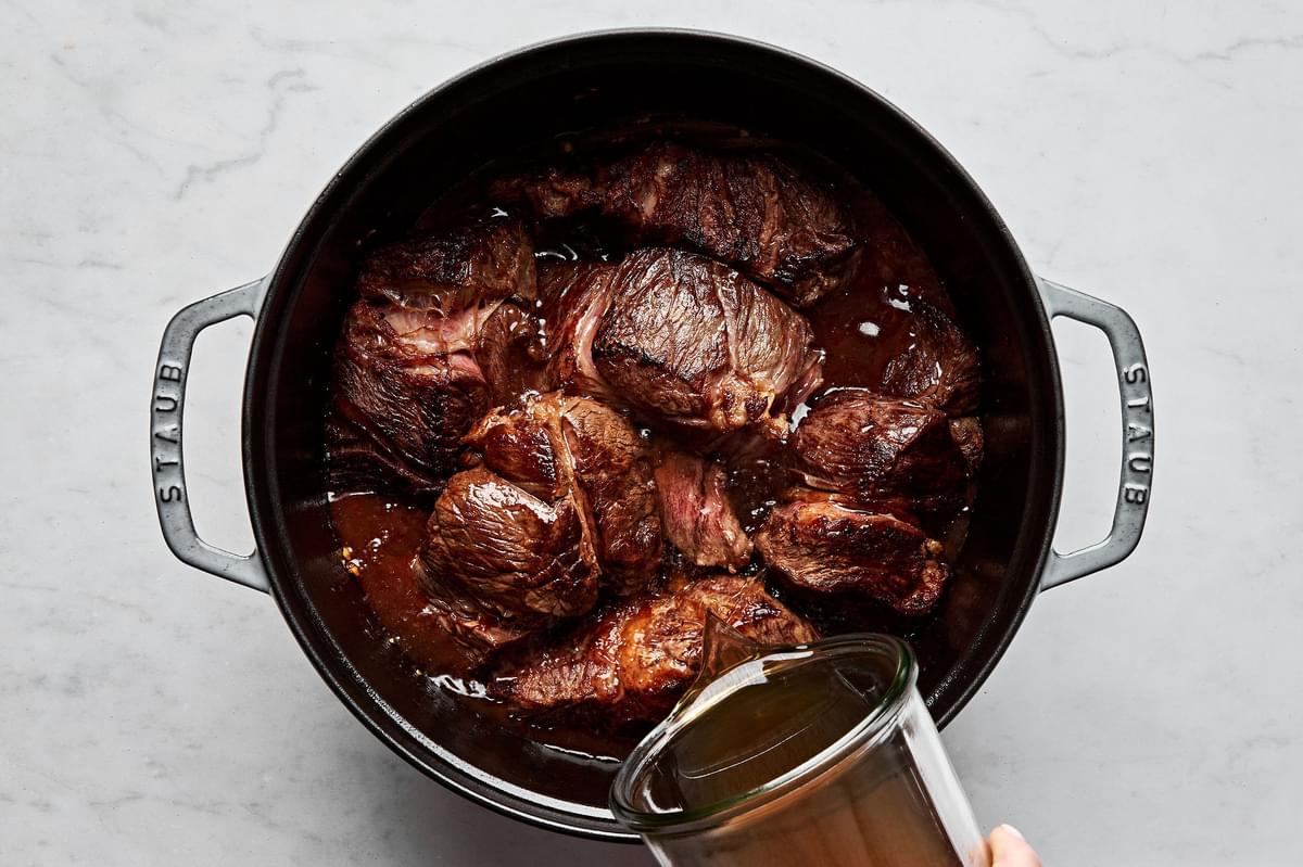 browned chuck roast in a pot with onions, garlic, ginger, beef stock, gochujang paste, brown sugar & soy sauce
