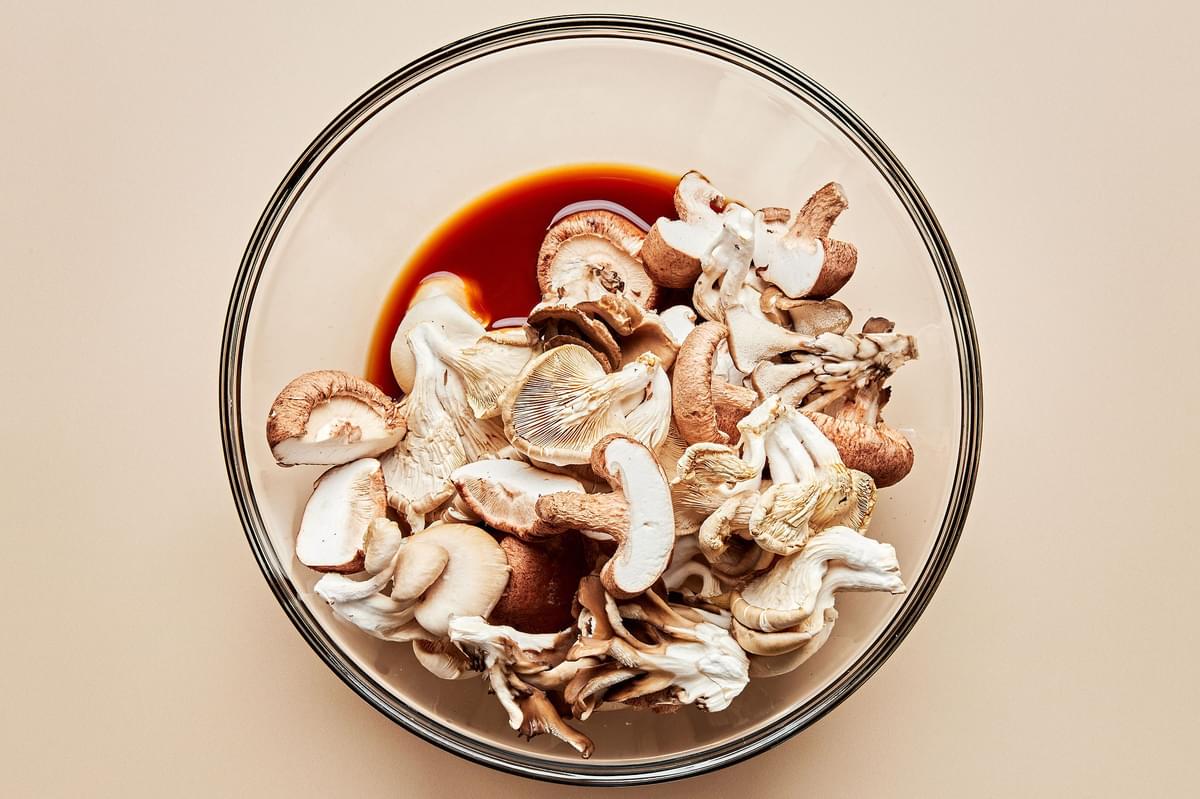 mushrooms being tossed with soy sauce, vinegar, brown sugar, and cornstarch in a bowl