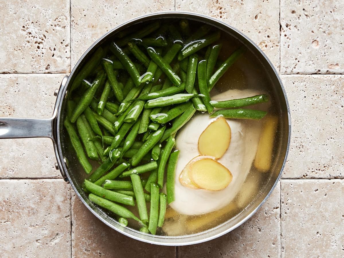 chicken and green beans being cooked in a large pot of water
