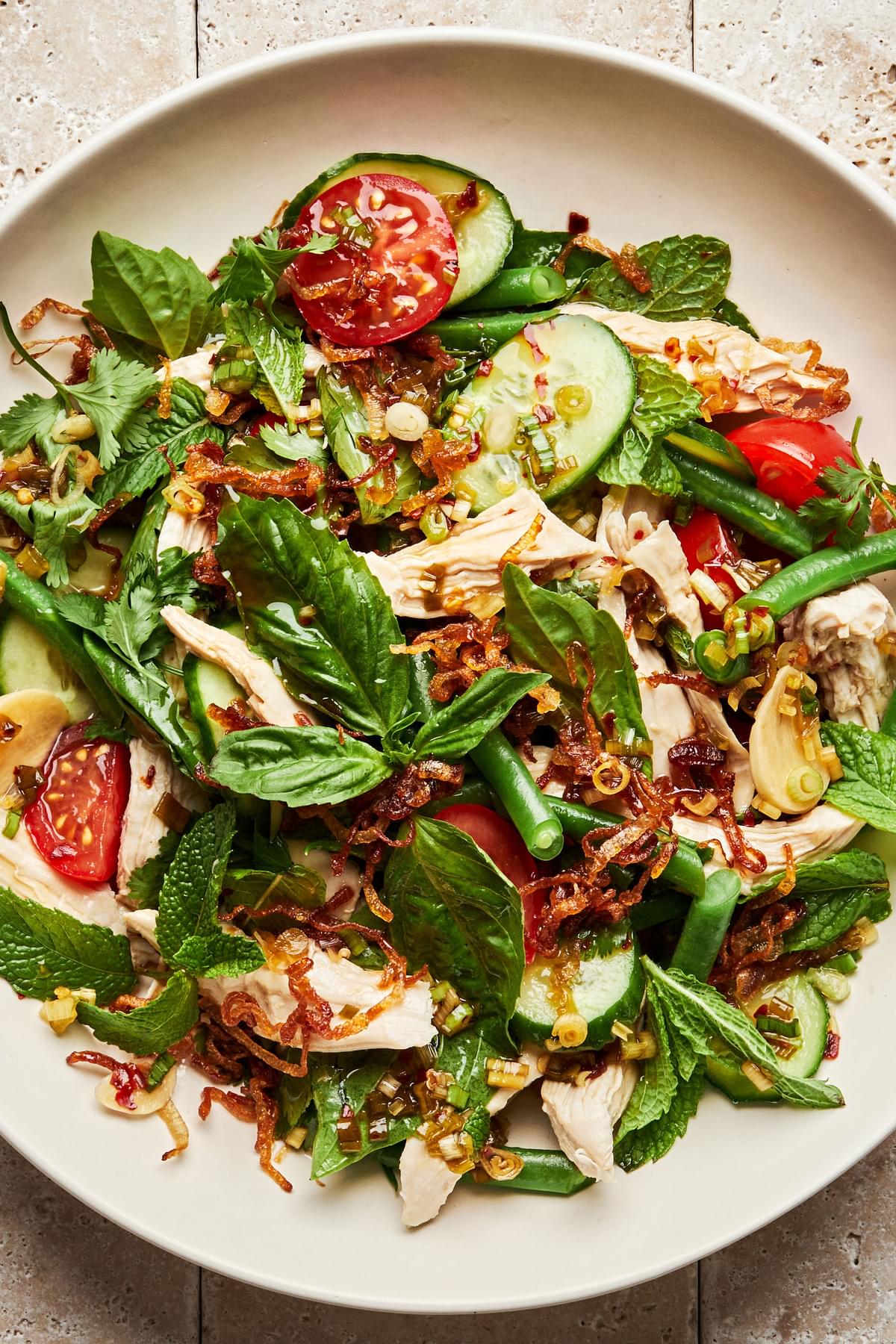 lemongrass chicken herb salad made with basil, mint, green beans, tomatoes, cucumbers and fried shallots