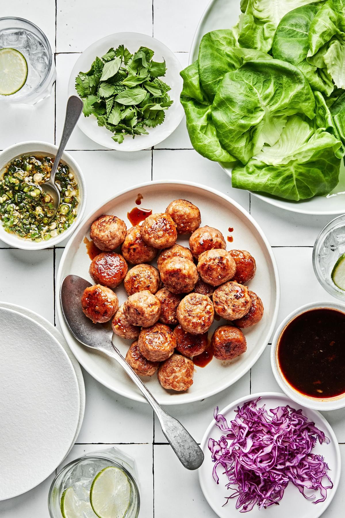 lemongrass meatballs, butter lettuce, brown sugar sauce, green onion oil and shredded red cabbage in bowls for lettuce cups