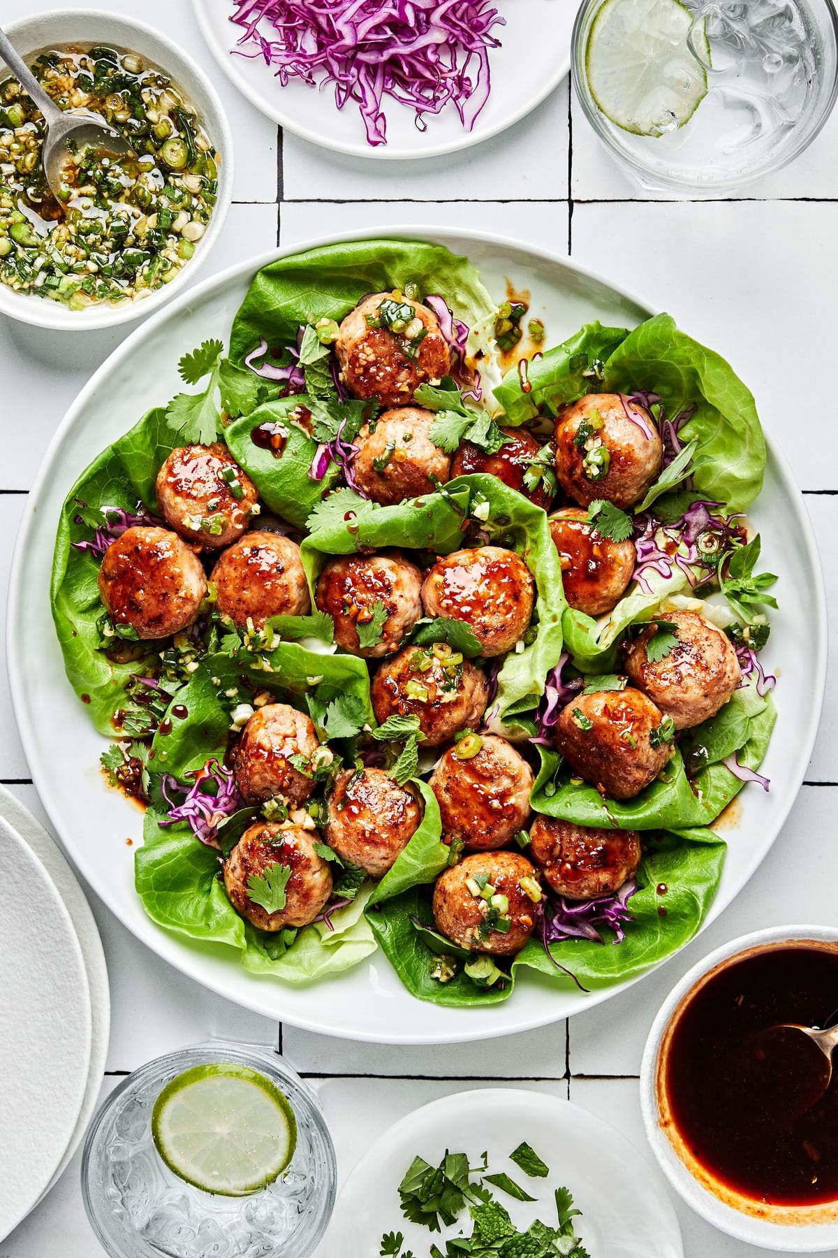 Lemongrass Meatball Lettuce Cups sprinkled with fresh herbs, drizzle with brown sugar sauce and green onion oil.