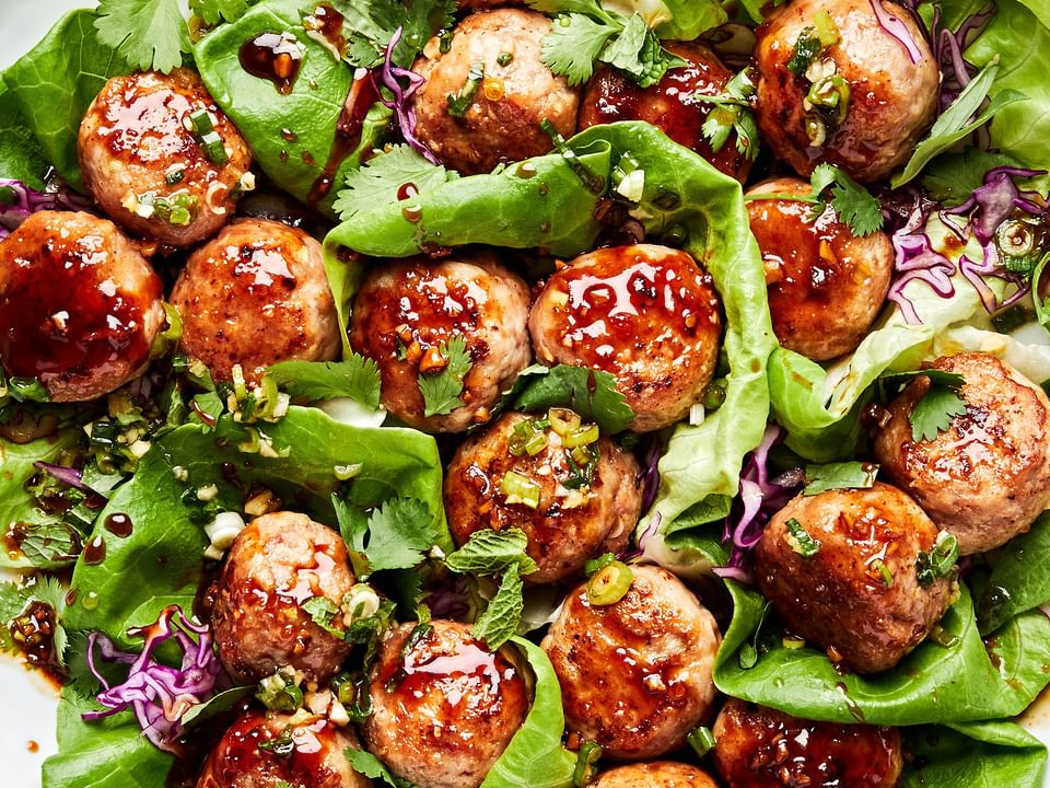 Lemongrass Meatball Lettuce Cups sprinkled with fresh herbs, drizzle with brown sugar sauce and green onion oil.