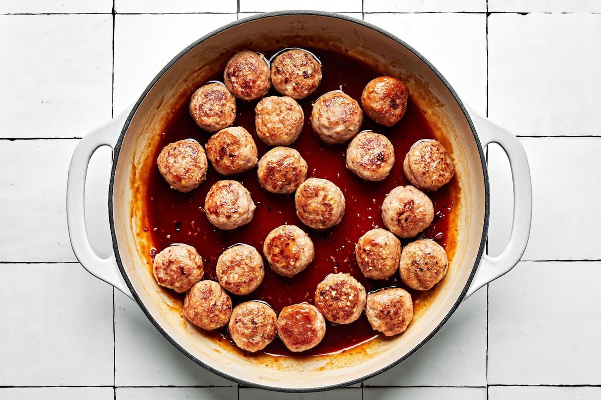 lemongrass meatballs being cooked in brown sugar sauce in a skillet