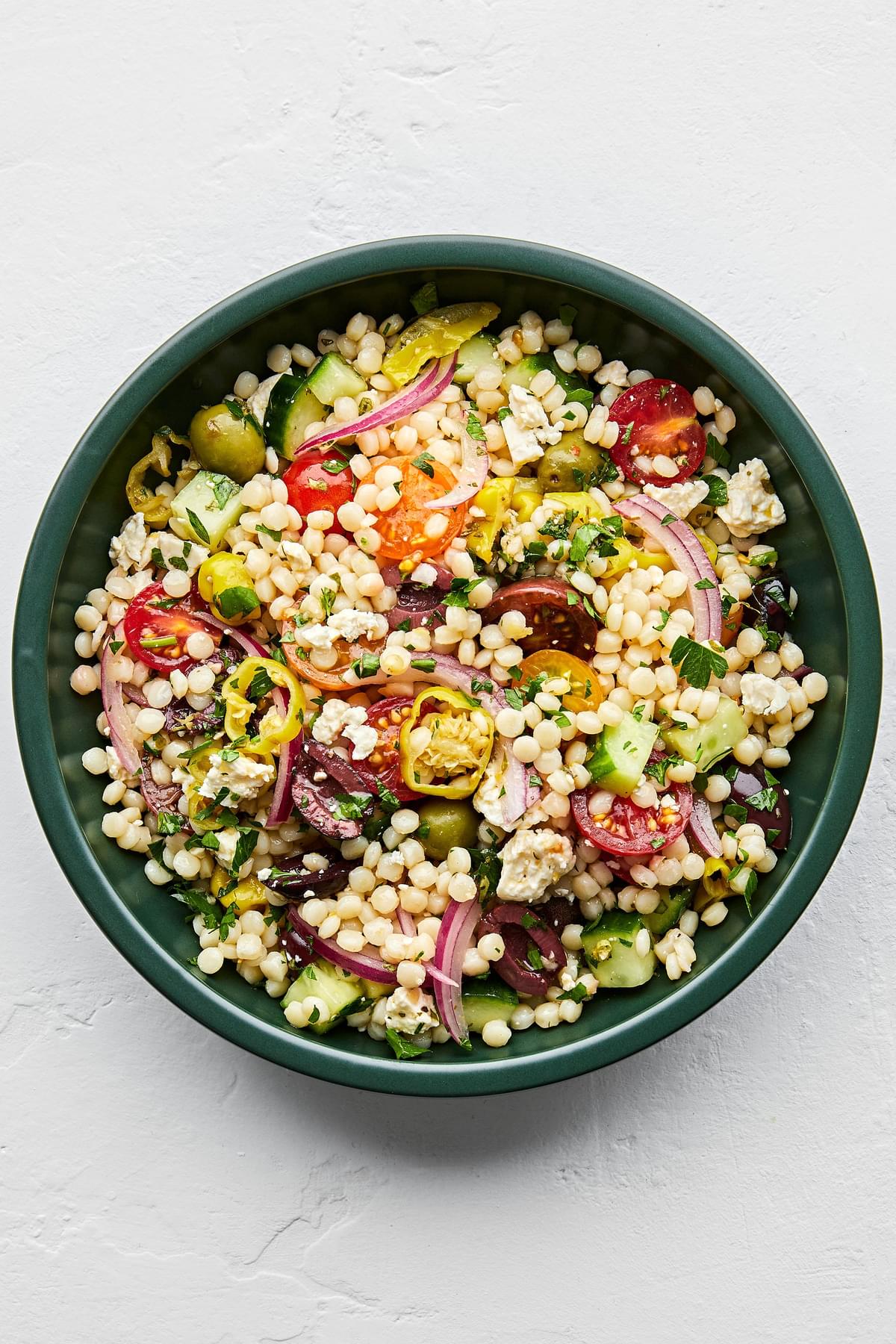 mediterranean couscous salad made with feta, greek olives, cucumber, tomato, pepperoncini, red onion and parsley