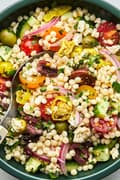 mediterranean couscous salad made with feta, Greek olives, cucumber, tomato, pepperoncini, red onion and parsley