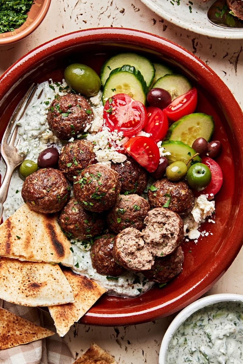 mediterranean meatballs with tzatziki served over rice pita bread, tomatoes, cucumbers and olives