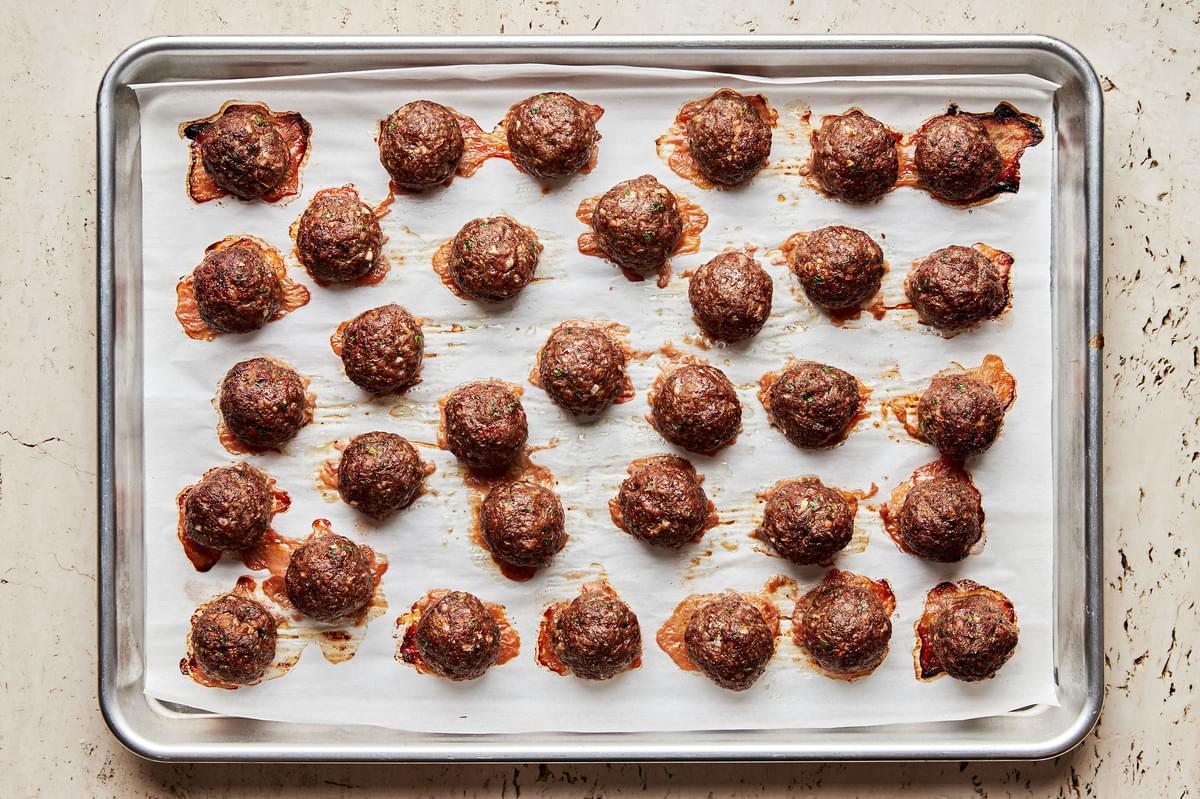 mediterranean meatballs made with ground beef, onion, spices, parsley, eggs & bread crumbs on a parchment lined baking sheet