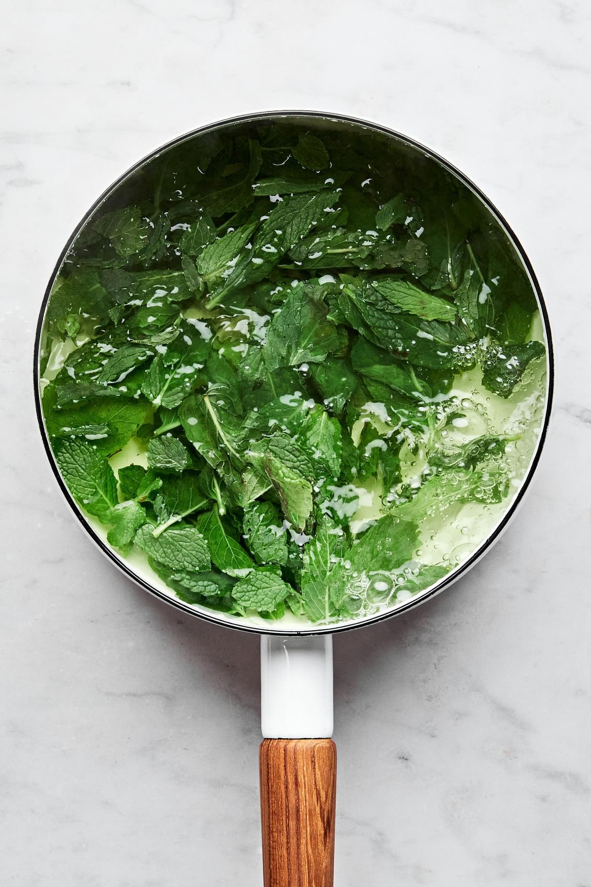 Fresh mint leaves in a small saucepan with 2 cups of water.