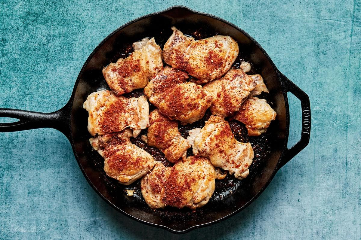 chicken thighs seasoned with salt, smoked paprika, chili powder, brown sugar and black pepper being cooked in a skillet