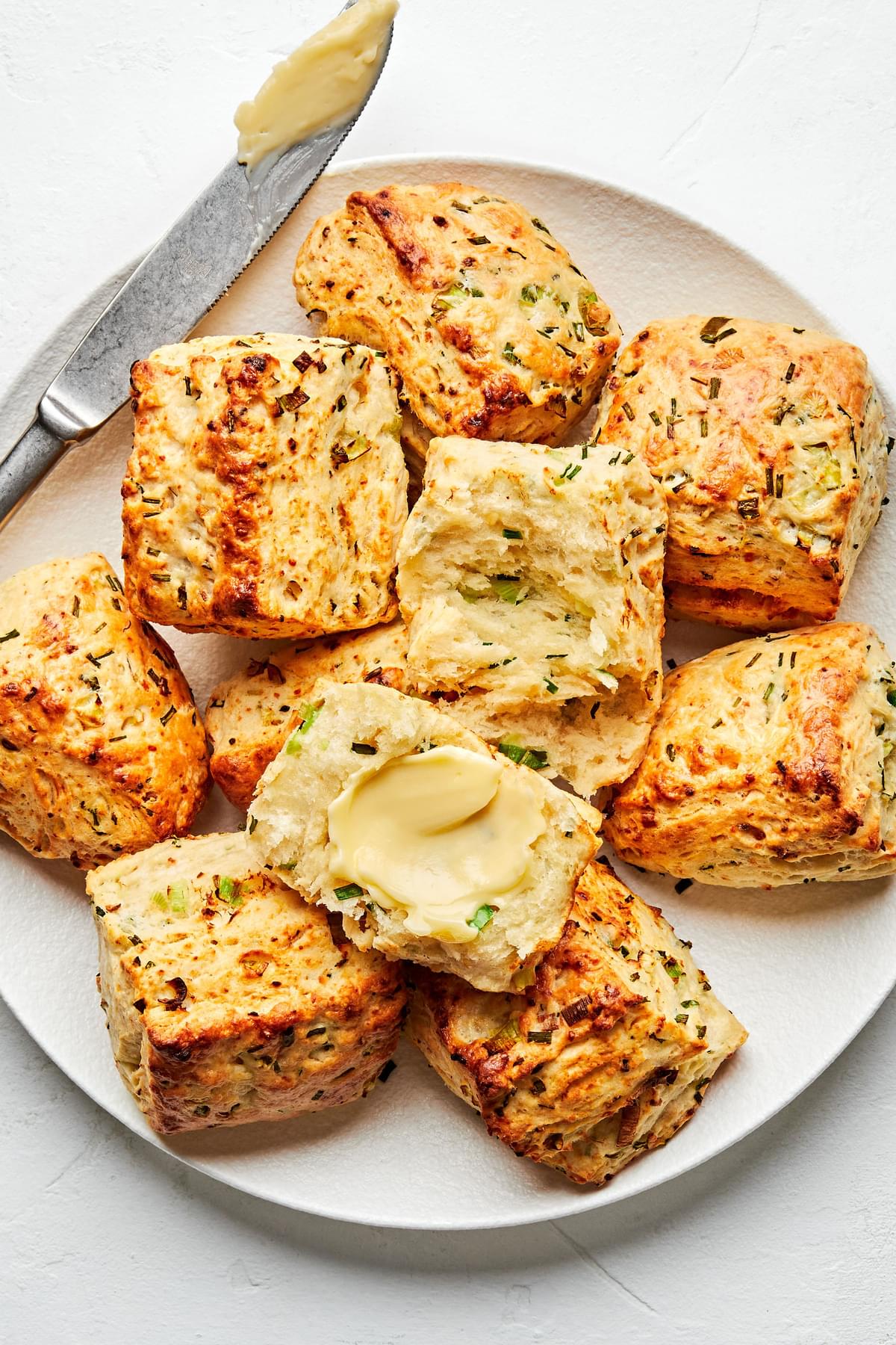 homemade onion chive biscuits being buttered on a plate