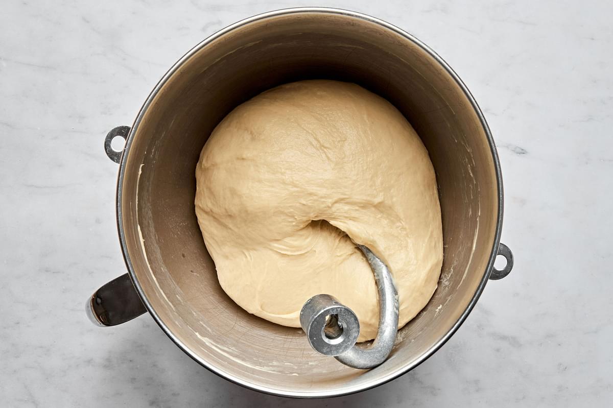 bread dough in a mixing bowl made with butter, milk, sugar, flour, active yeast, warm water and eggs.