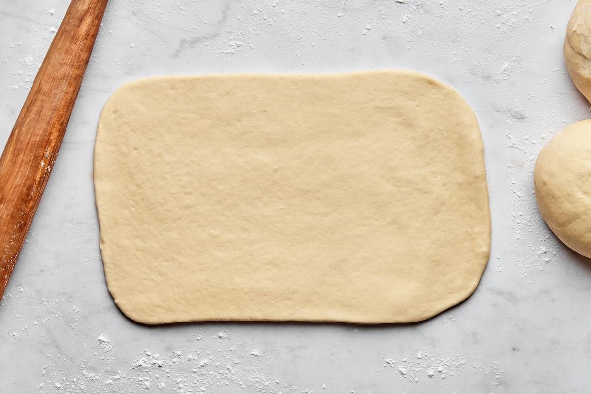 parker house rolled dough being rolled flat on a floured surface