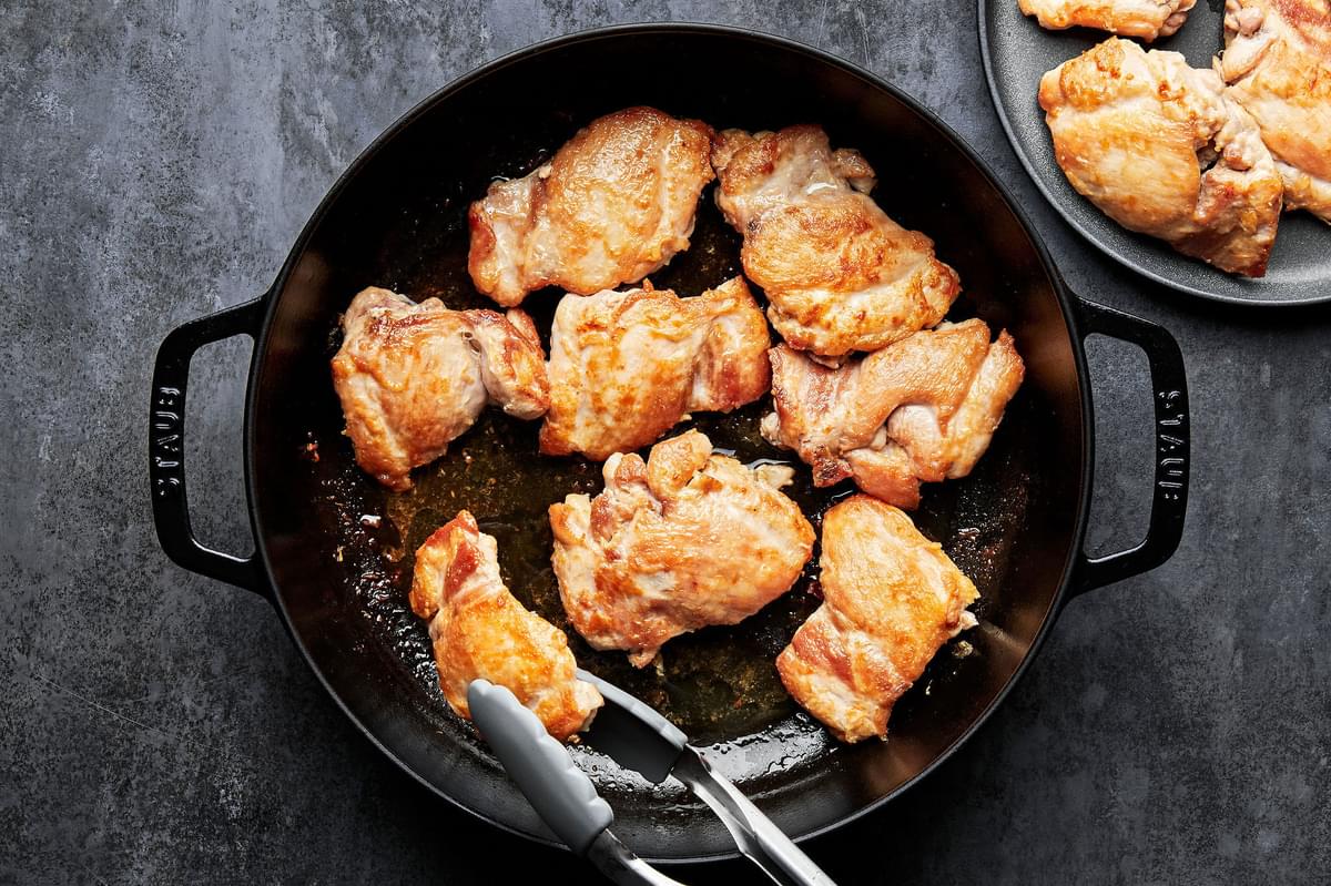 boneless, skinless chicken thighs seasoned with salt being cooked in a skillet