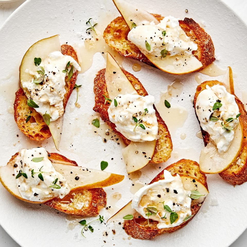 Pear and Burrata Crostini drizzled with sherry vinegar and honey and sprinkled with thyme, salt and pepper