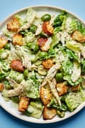 Pesto Caesar Salad with castelvetrano Olives, shredded chicken, parmesan and homemade croutons on a plate