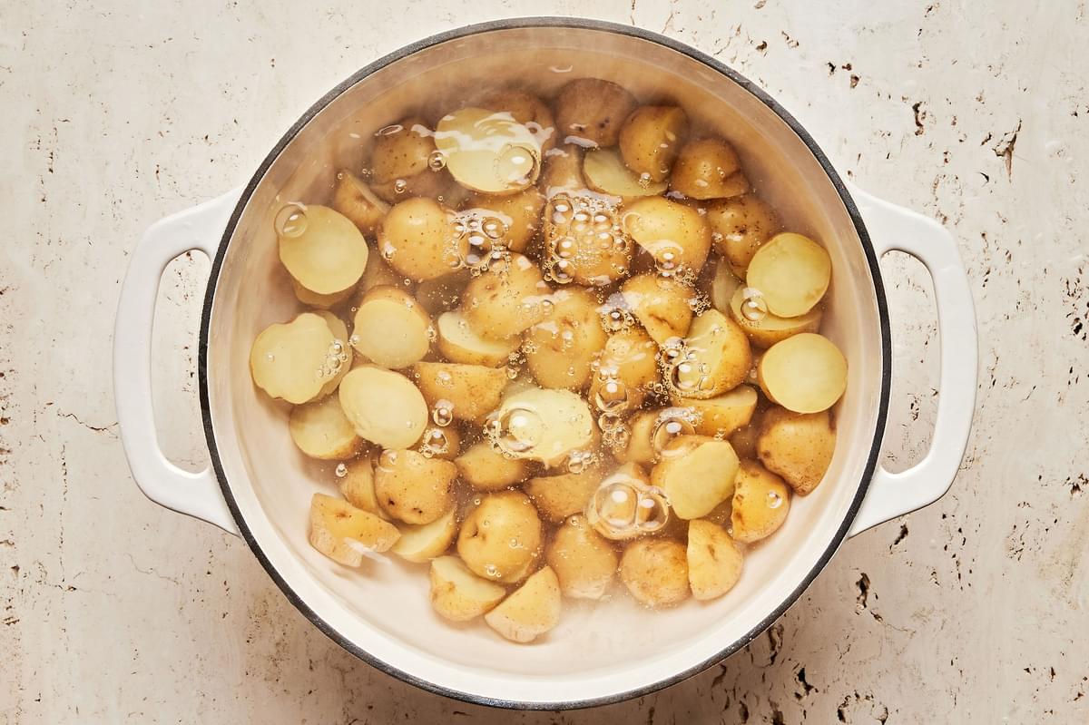 Yukon gold potatoes cut in half boiling in a pot of salted water