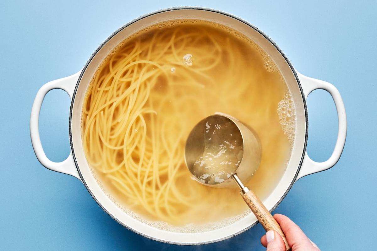 spaghetti noodles being cooked in boiling water