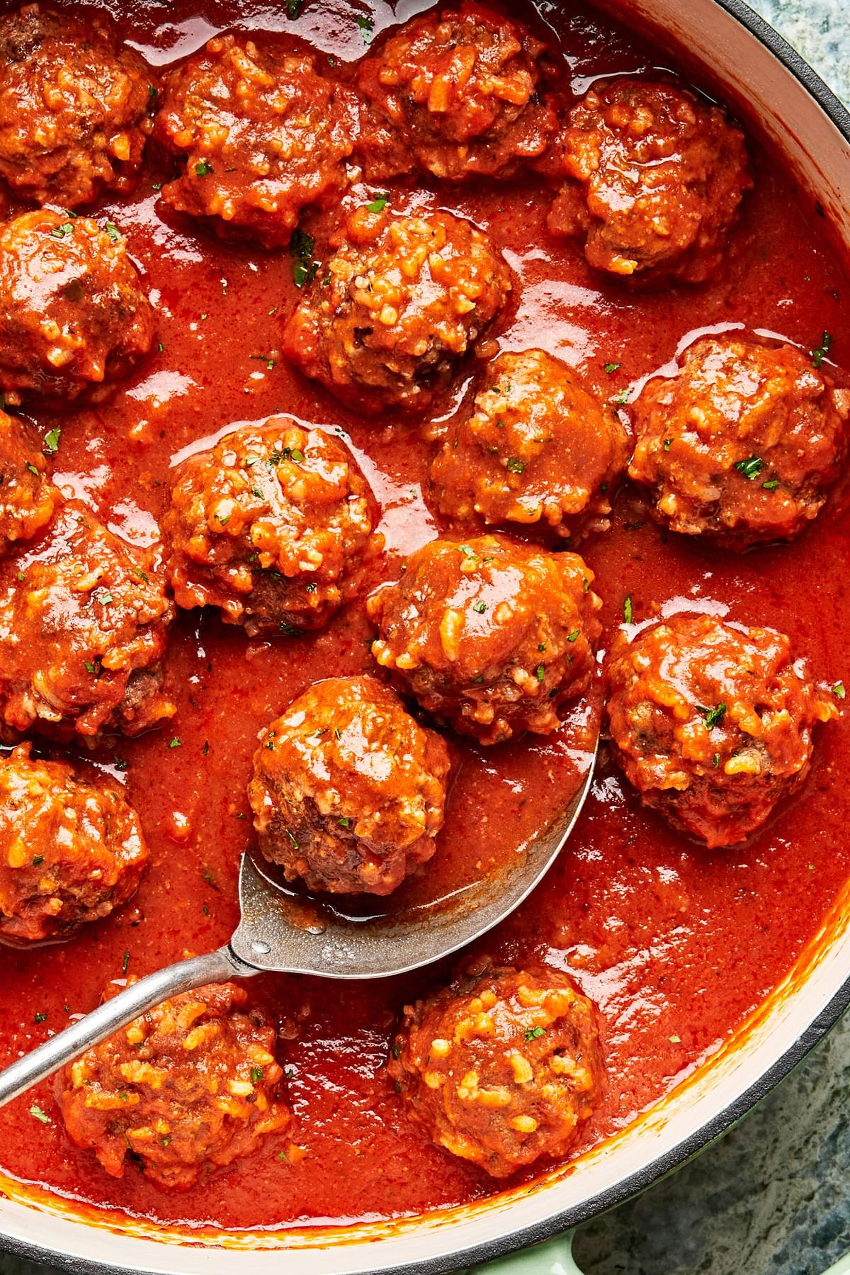 homemade porcupine meatballs and tomato sauce in a skillet with a spoon