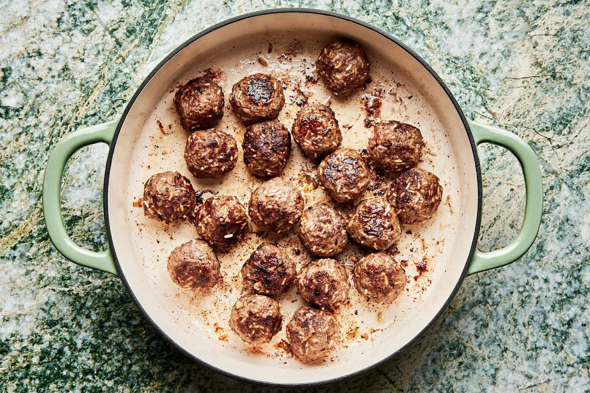 homemade porcupine meatballs being cooked in olive oil in a skillet
