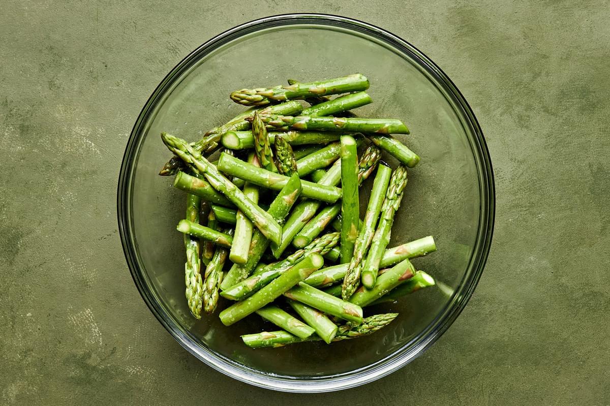 asparagus tossed with olive oil and salt in a glass bowl