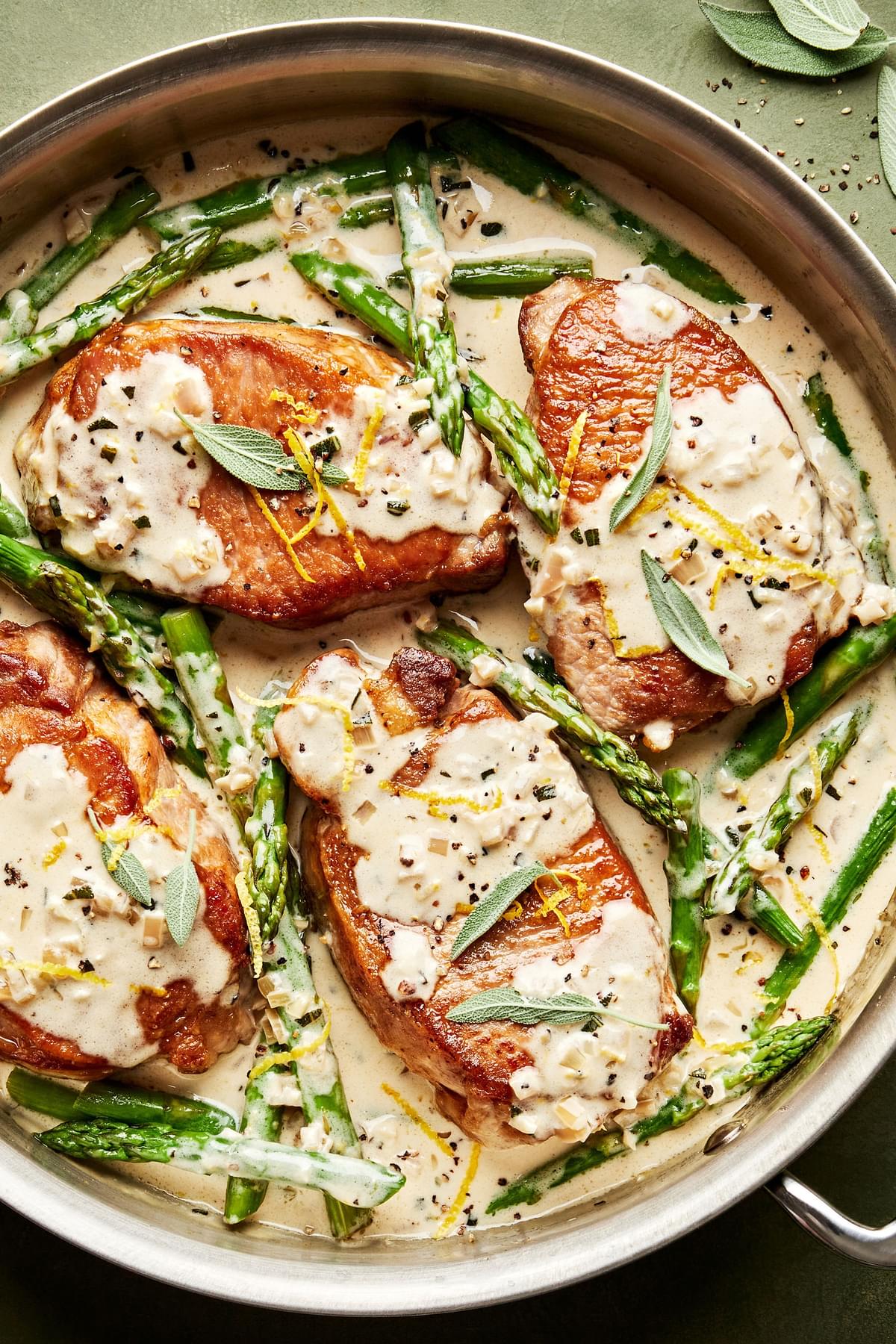 homemade Pork Chops with Asparagus and a Lemon Sage Cream Sauce in a skillet
