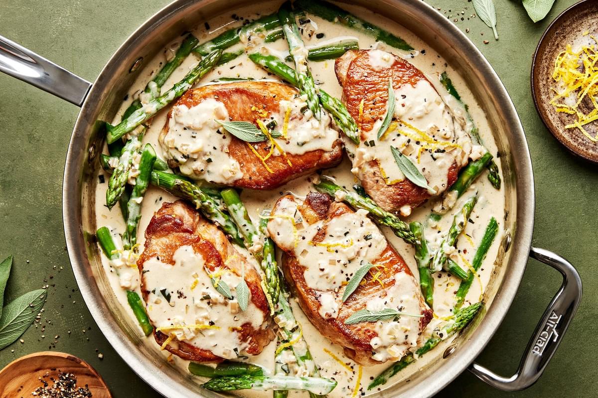 homemade Pork Chops with Asparagus and a Lemon Sage Cream Sauce in a skillet